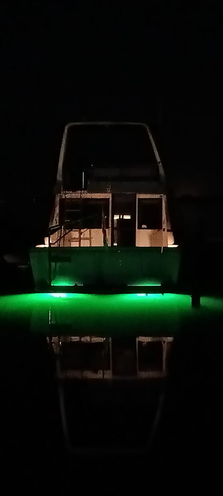 Motorboot bij nacht met groene onderwaterverlichting